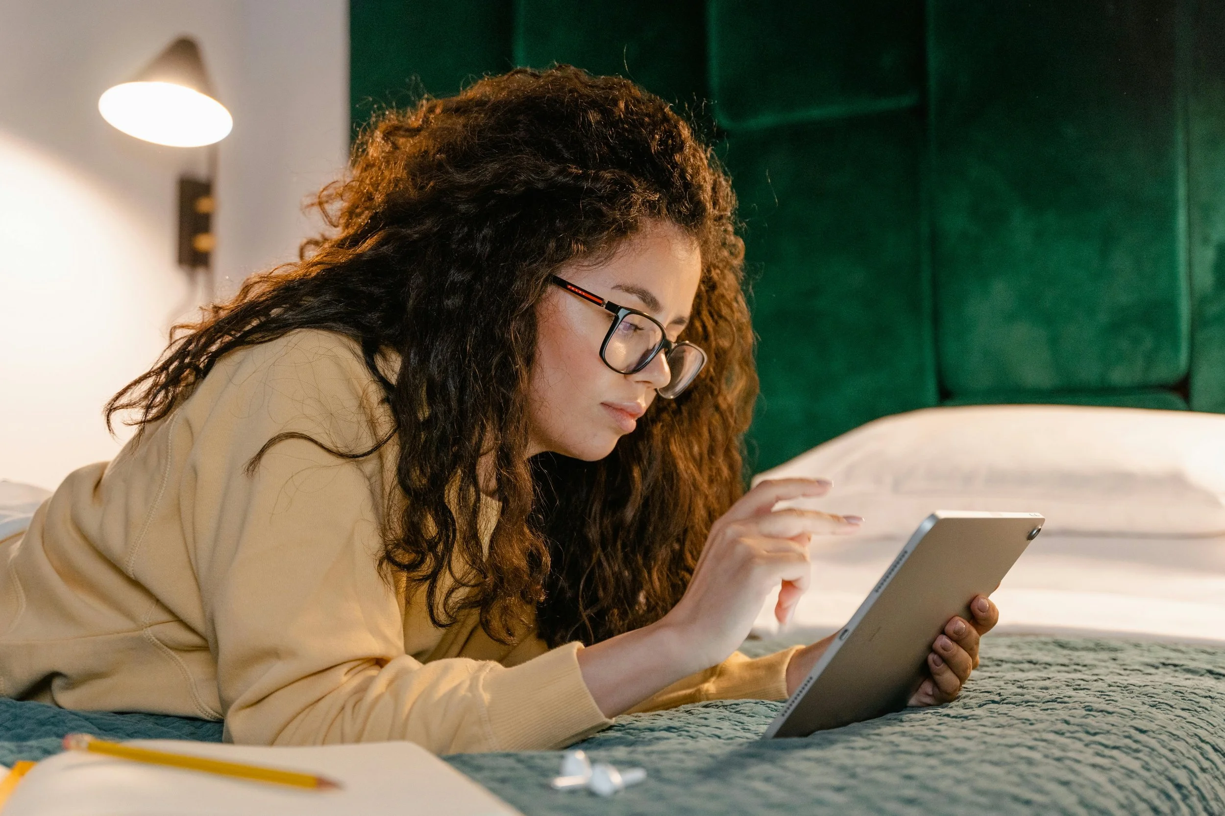 Woman relaxing on bed reading on a tablet