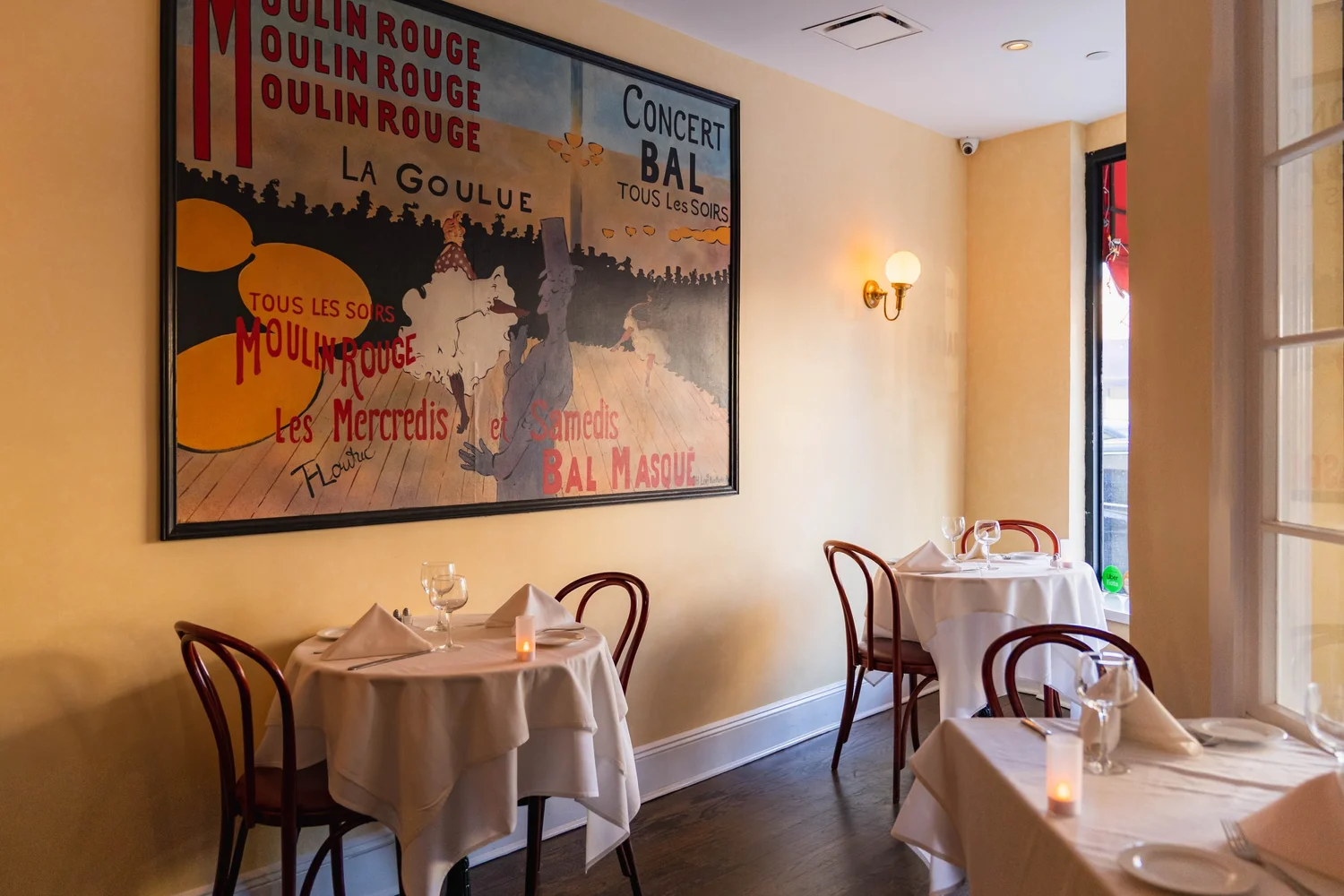 Moulin Rouge artwork and warmly lit tables at Brasserie Le Steak