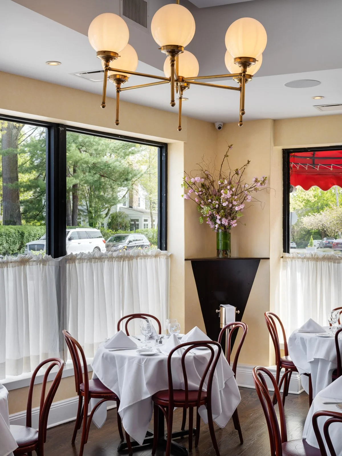 Sunlit dining room with globe chandelier, flowers and white tablecloths