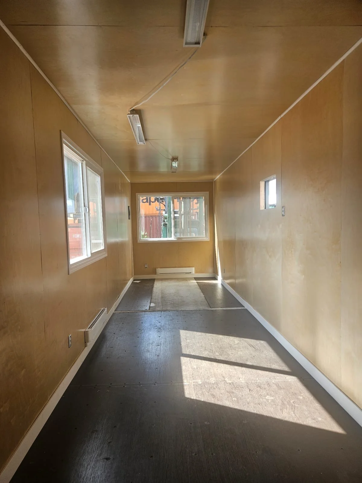 Insulated and framed interior of Kathy Bird's modified shipping container, with windows and electrical outlets