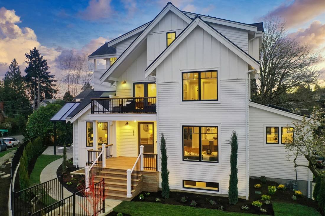 A white modern farmhouse lit at twilight