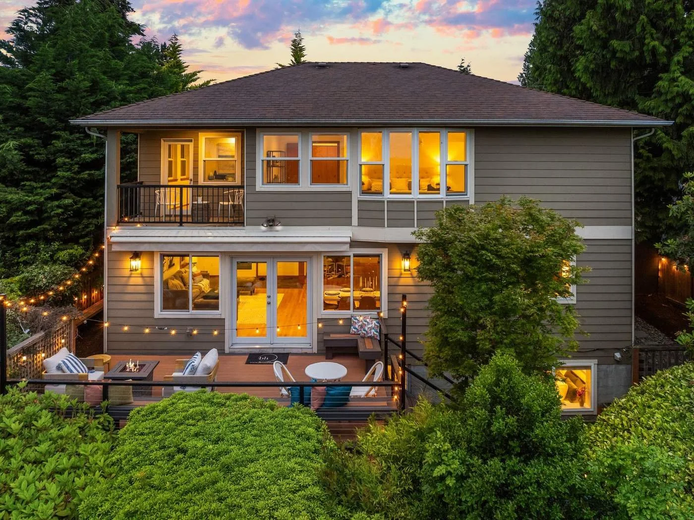 A two-story home with warm lights glowing at dusk