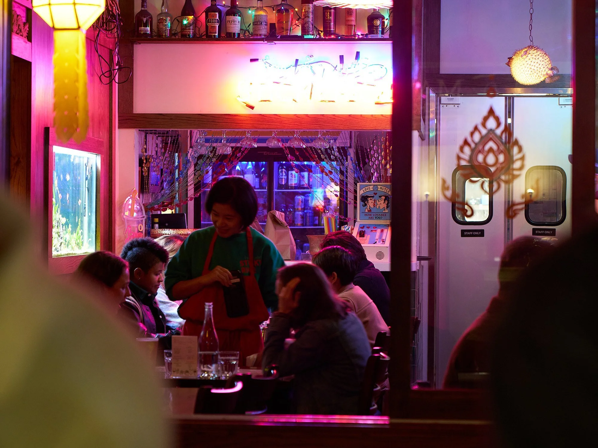 A server taking an order in the neon-lit dining room at Sticky Rice Echo Park