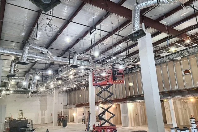 Car dealership interior during construction, with ceiling lighting and power rough-in installed