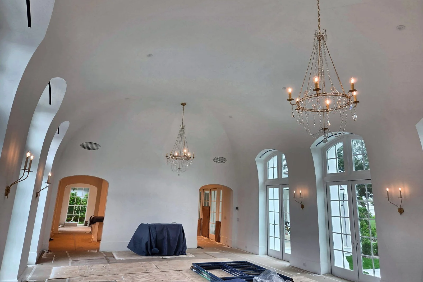 Great room in a high-end custom home with chandeliers, wall sconces and recessed speakers