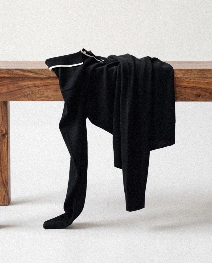 Black knitwear draped on a wooden bench