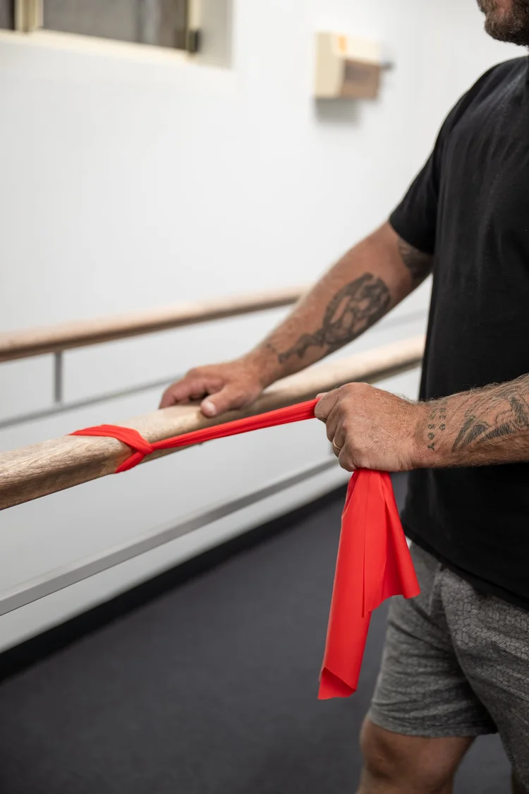 A client using a resistance band at the parallel bars