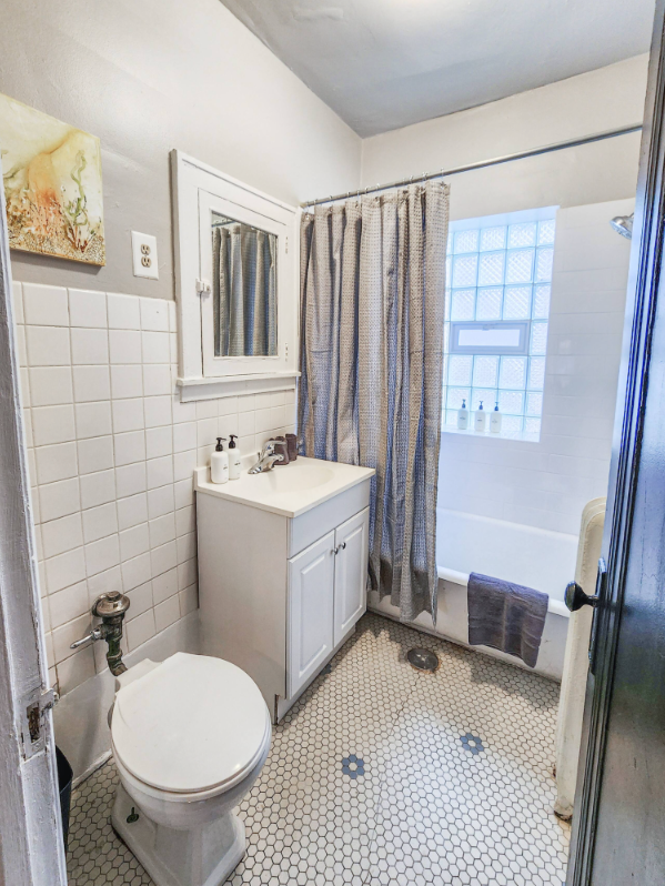 A Bedder Place: Bathroom with toilet, vanity, mirrored cabinet, bathtub and shower curtain.