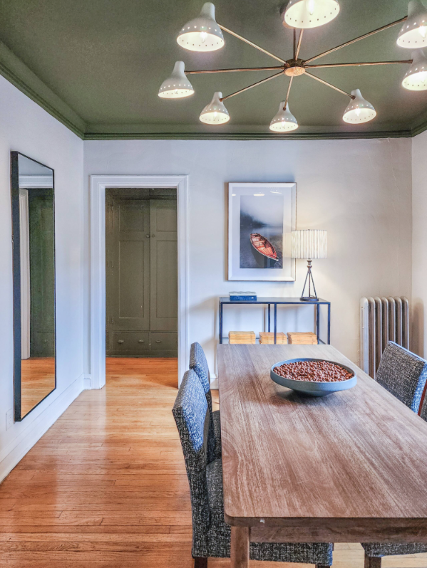 A Bedder Place: Portrait view of the dining table, chairs, branching ceiling fixture, mirror and console.