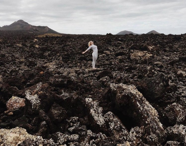 Oceana is doing a standing backbend in a field of lava located in Lanzarote, Canary Islands.