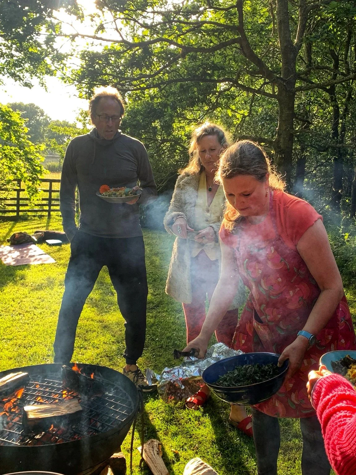 Friends sharing food around an outdoor fire