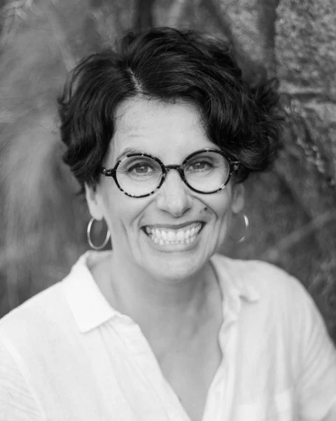 Hannele Korhonen, smiling, in round glasses and a white shirt