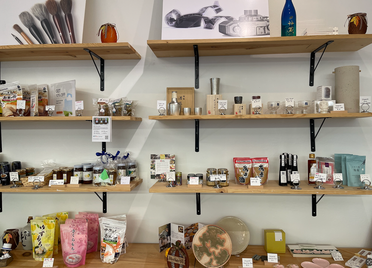 Photo of the new goods that are for sale at the Japantown Cultural District Visitor Center.  Mokumegane Art and Jewelery, Garlic Oil by Kana's Kitchen and Holiday gift sets.