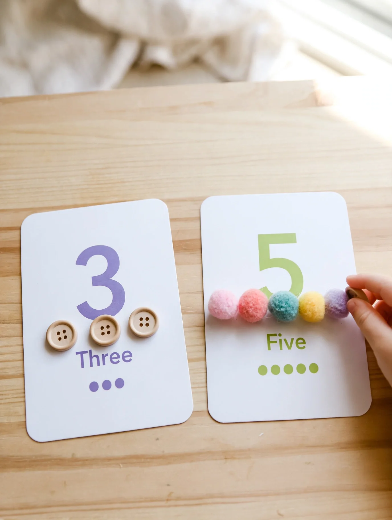 Counting real objects onto number cards to teach a toddler to count