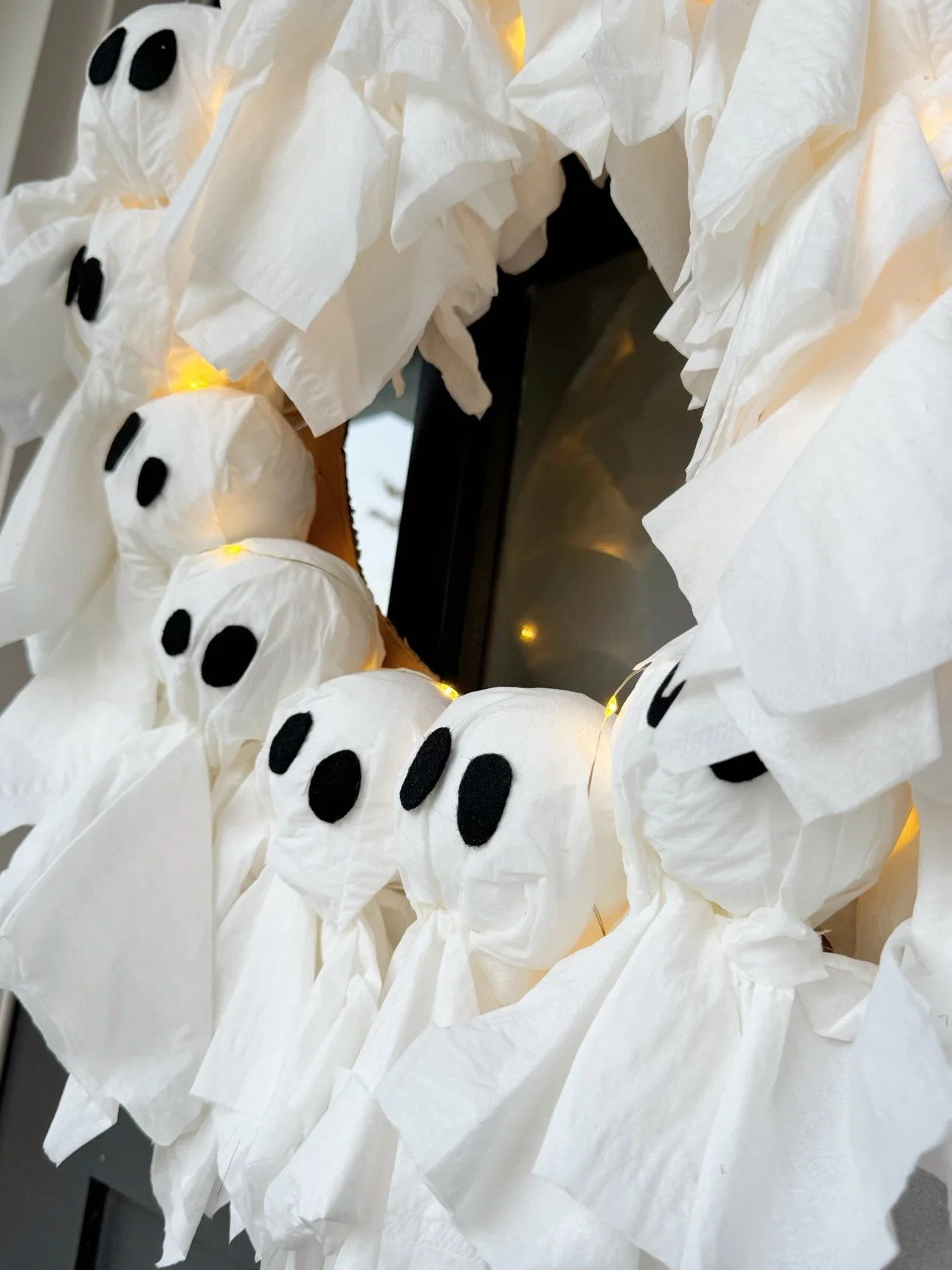 Side view of tissue ghosts on the wreath with warm fairy lights glowing between them