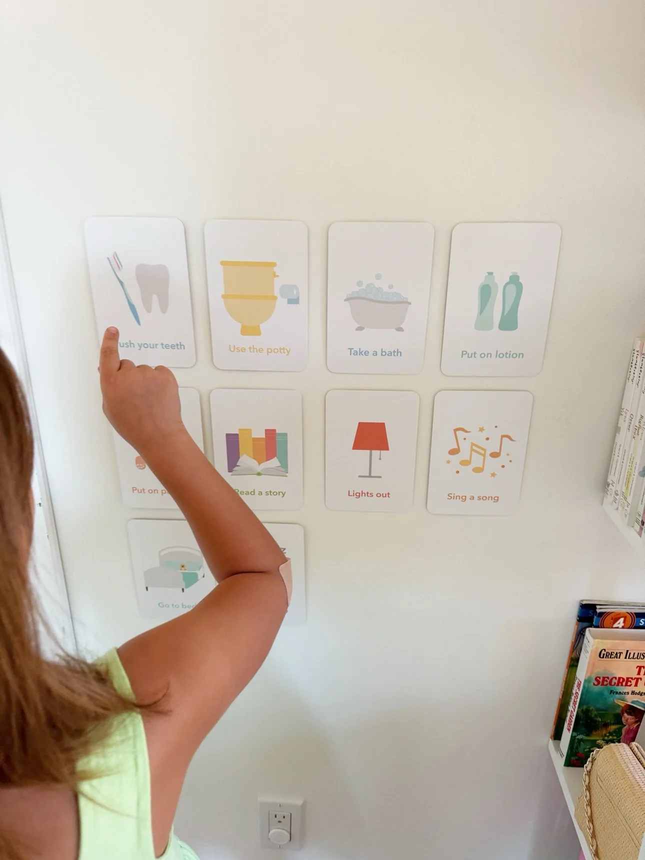 Toddler pointing to bedtime routine cards on the wall