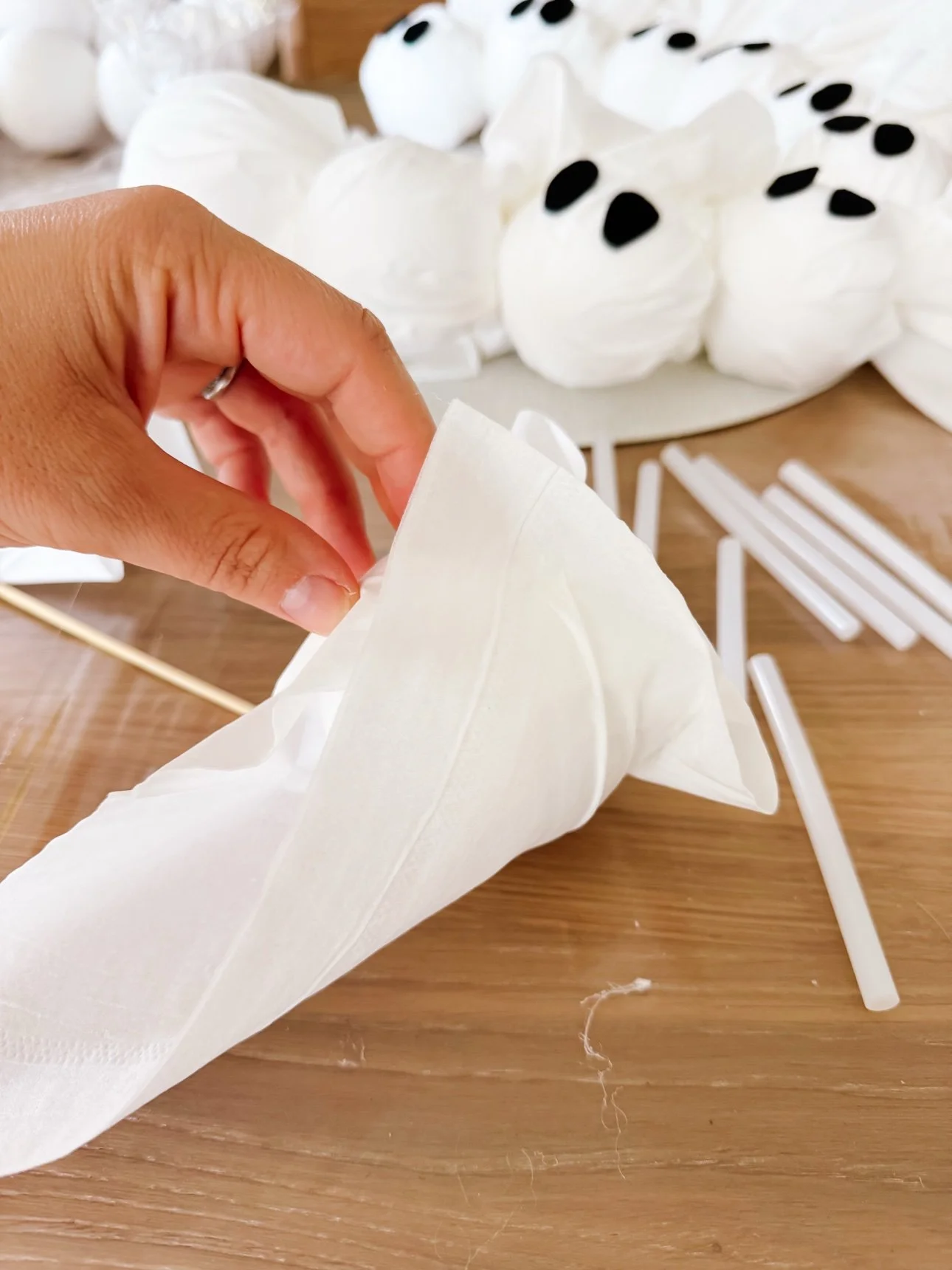 Foam ball wrapped in a white tissue on a table with craft supplies nearby