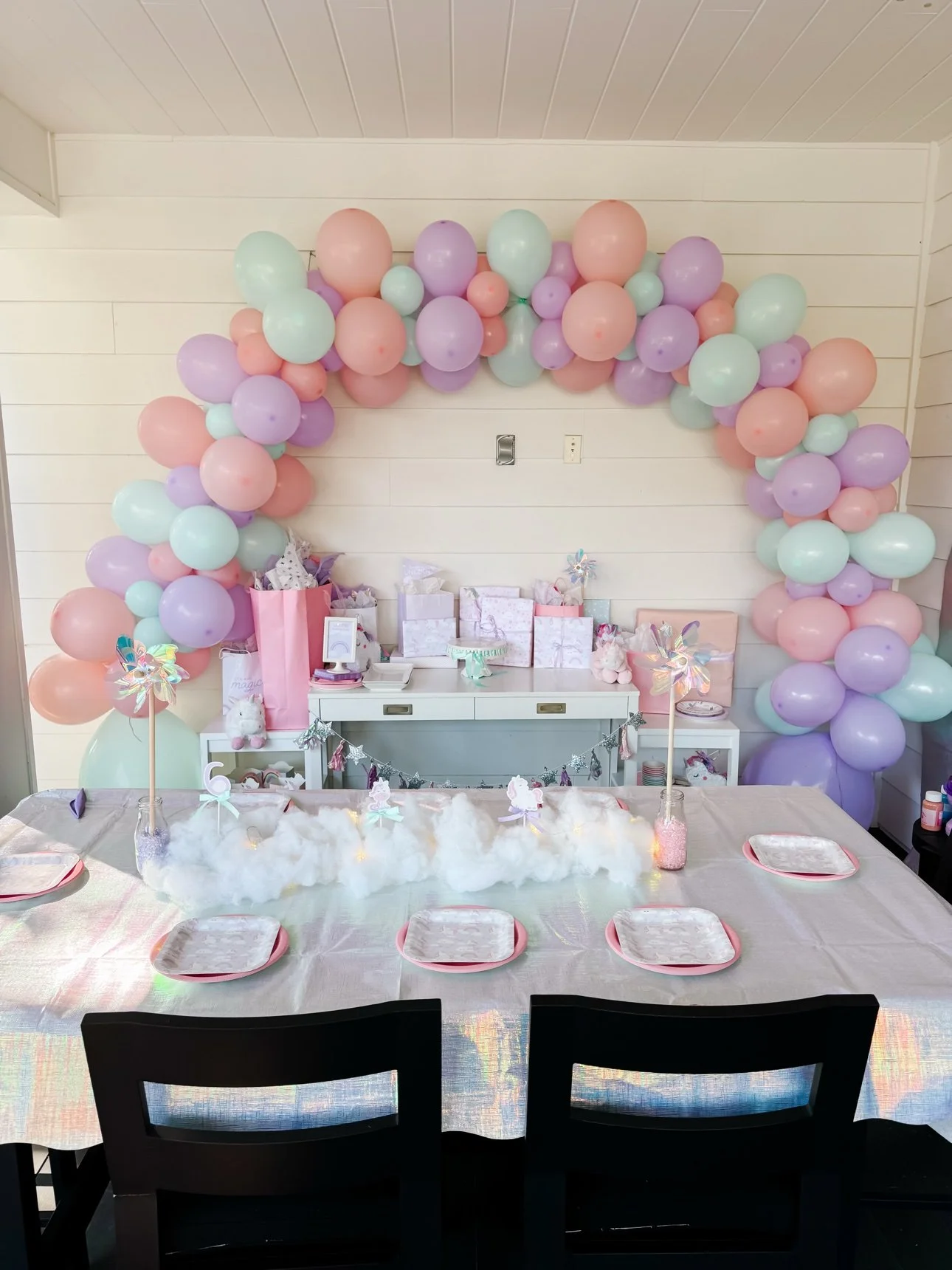 Outdoor unicorn party setup with balloon arch, dessert table and kids table