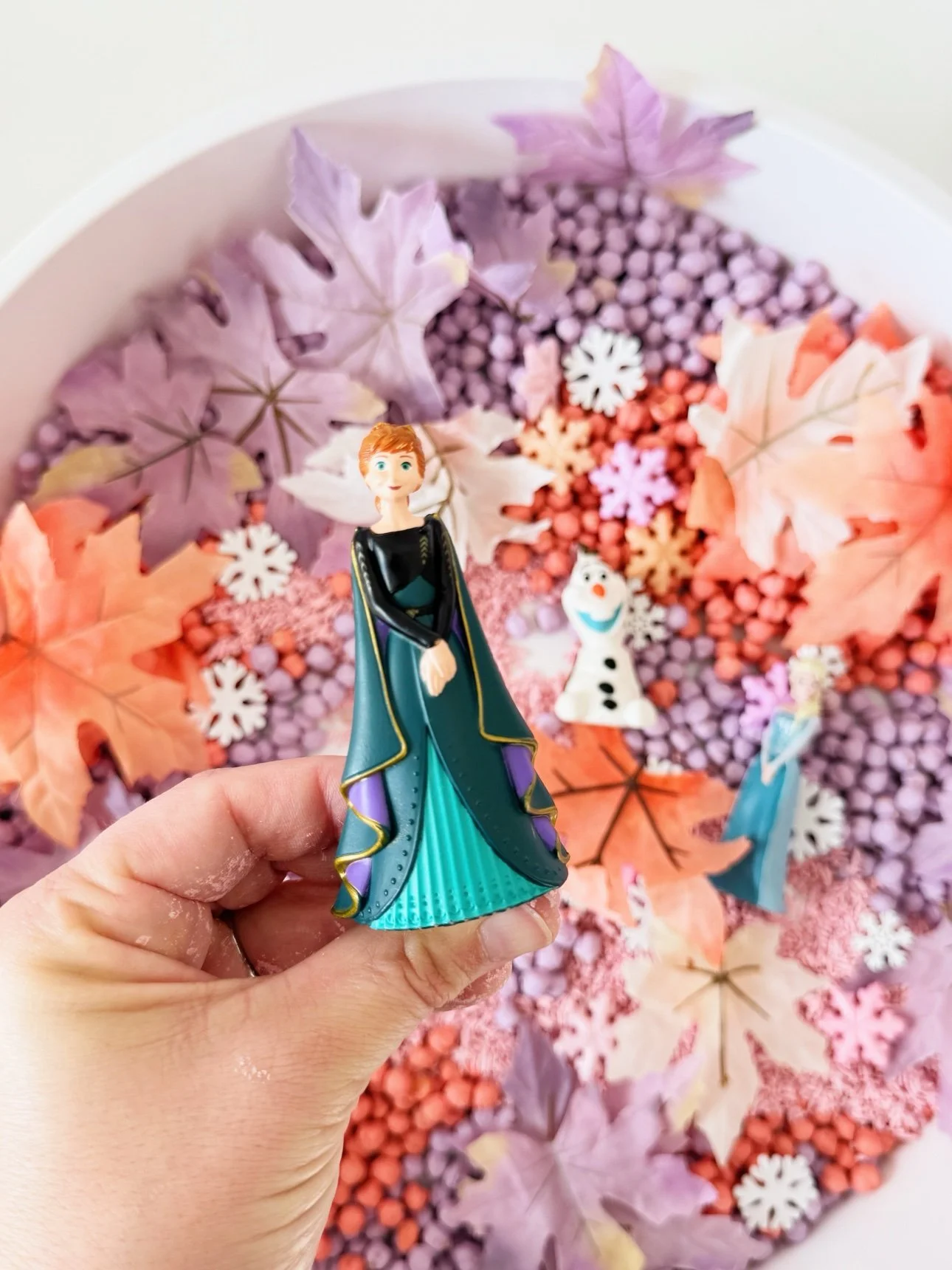 Anna figurine held over the fall frozen sensory bin