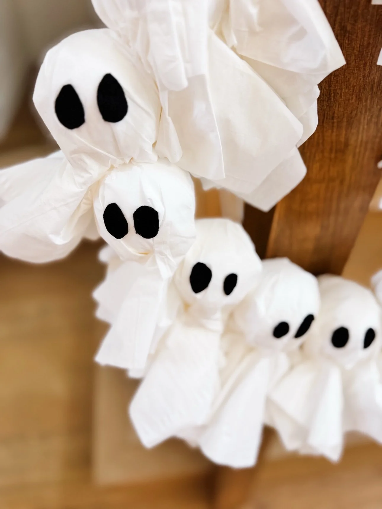 Close-up of three tissue ghosts with black felt eyes on the wreath