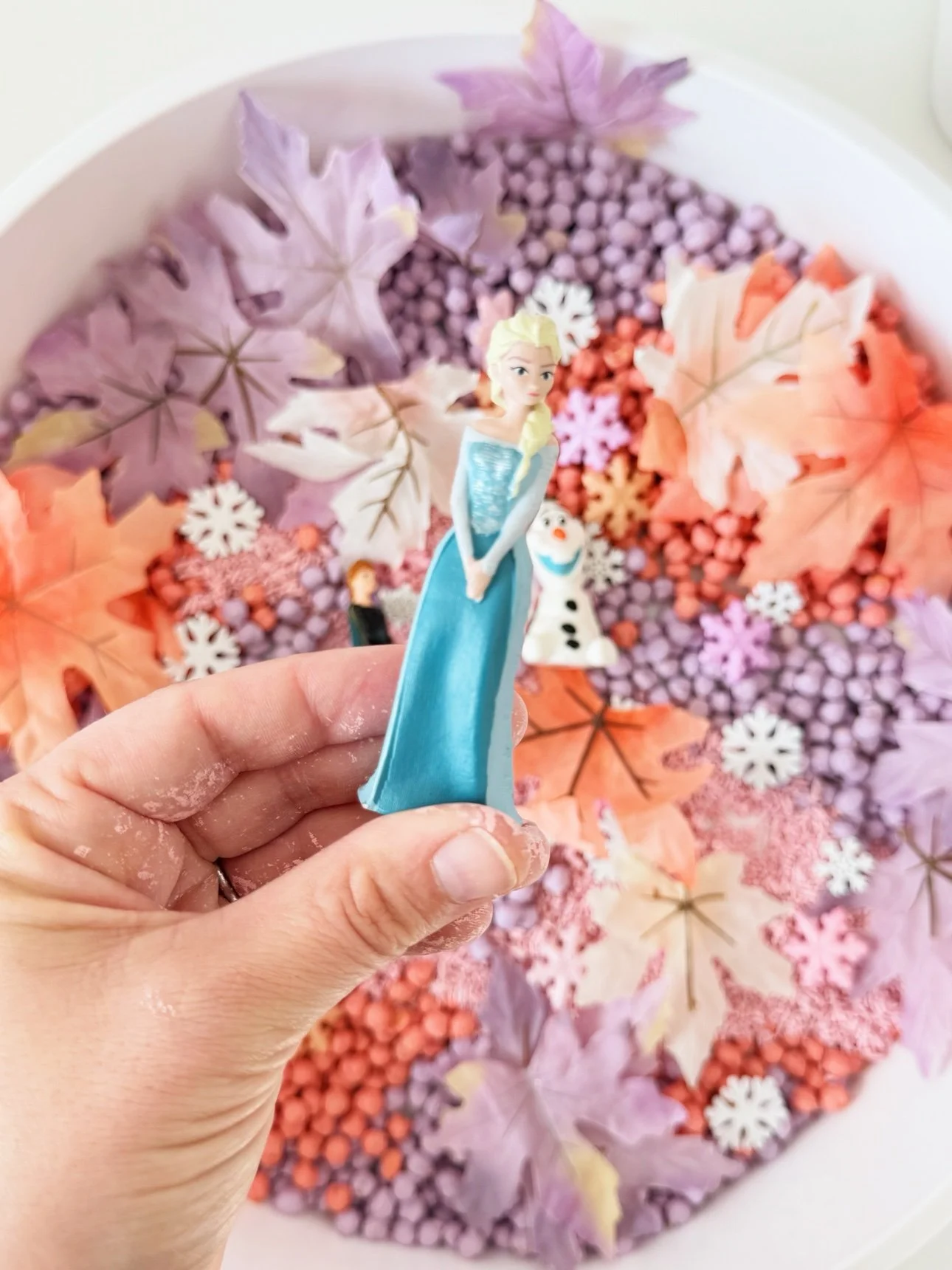 Elsa figurine held over the fall frozen sensory bin