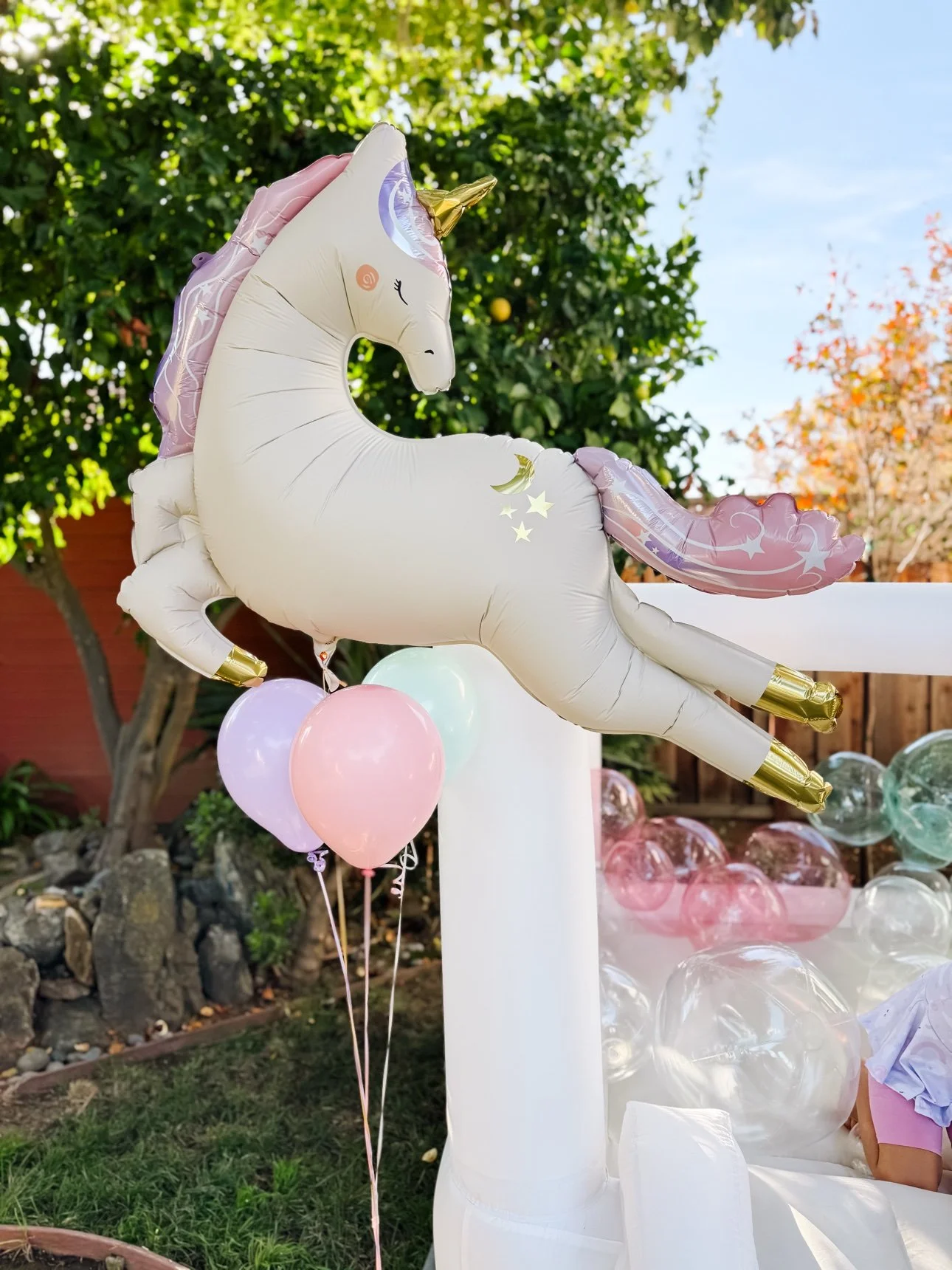 White bounce house decorated for a unicorn birthday party