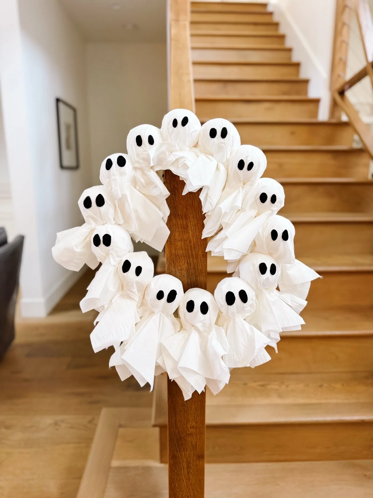 Ghost wreath hanging on a wooden stair post indoors
