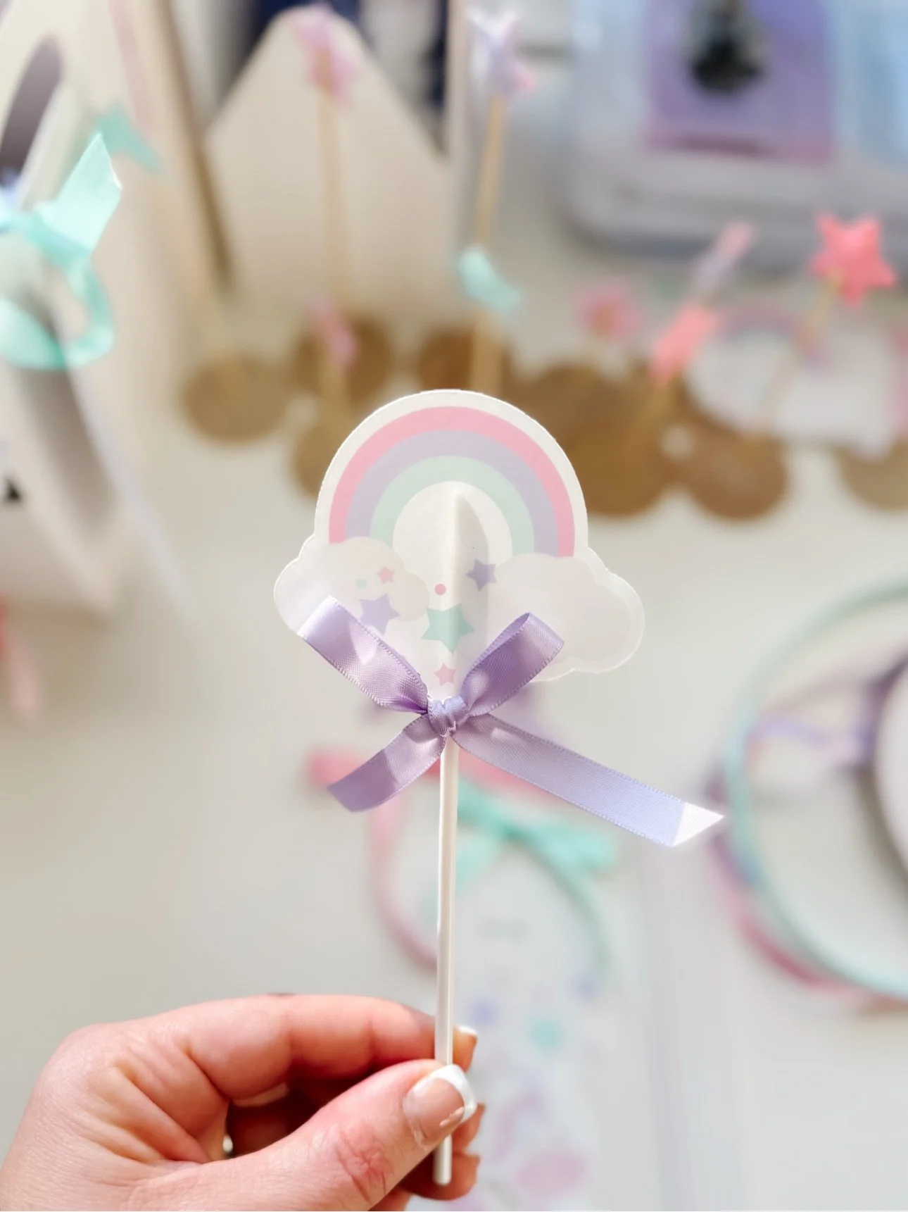 Hand holding a DIY rainbow unicorn cupcake topper