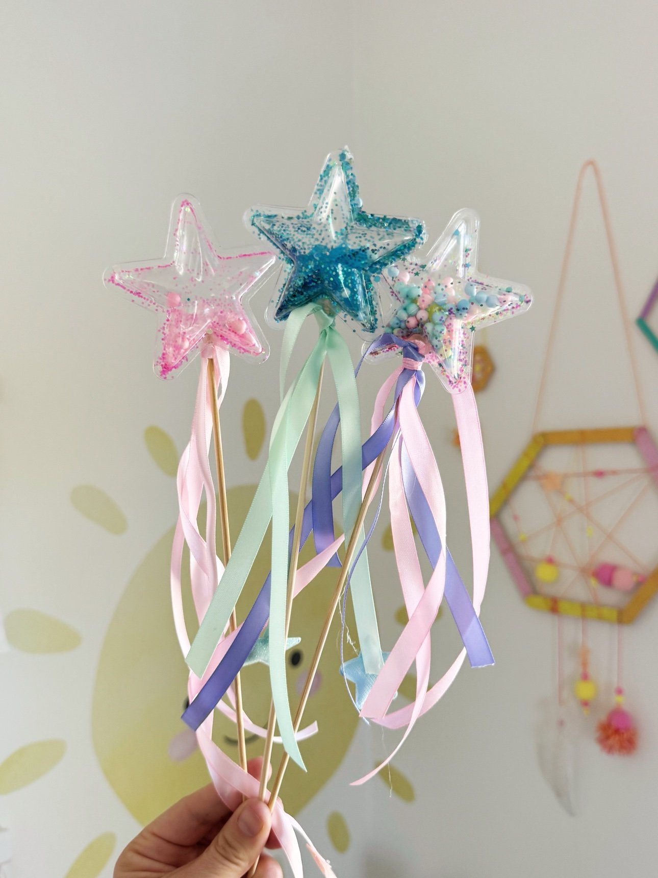 Three finished star shaker wands in pink, teal, and pastel