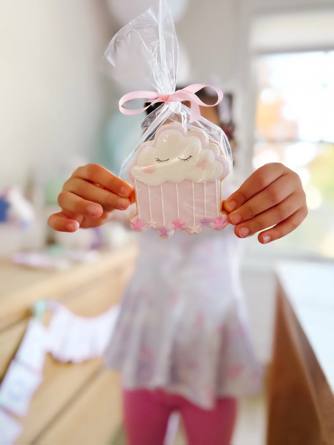 Child holding a wrapped cloud-shaped unicorn party cookie favor