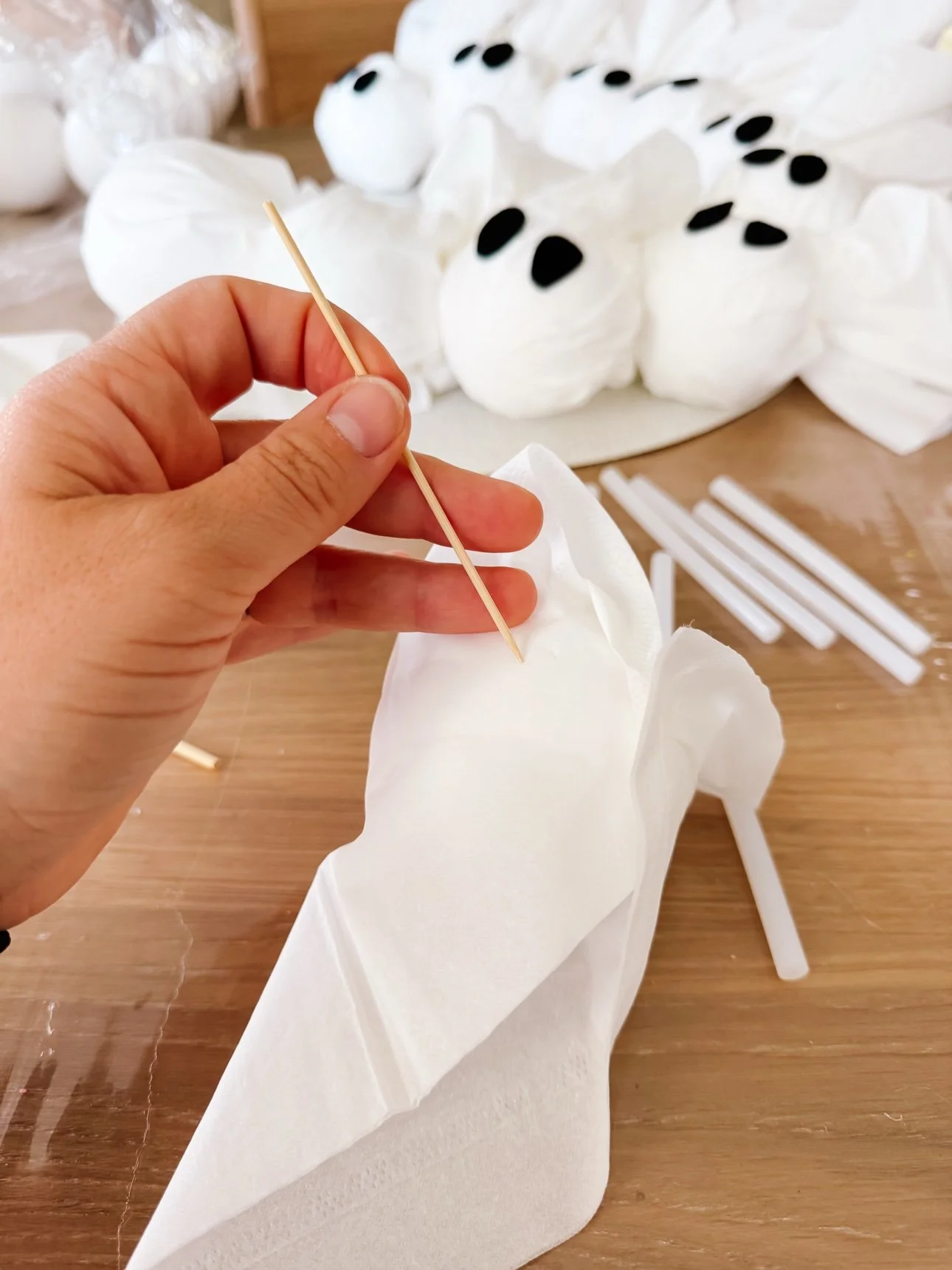 Hand holding a craft stick against a tissue ghost during assembly