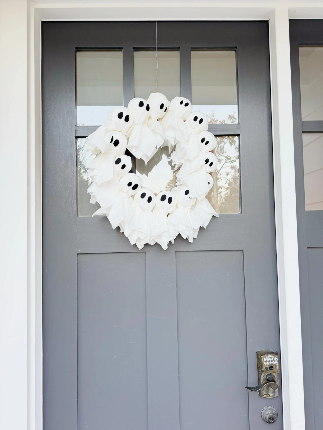 Finished ghost wreath of tissue ghosts hanging on a gray front door