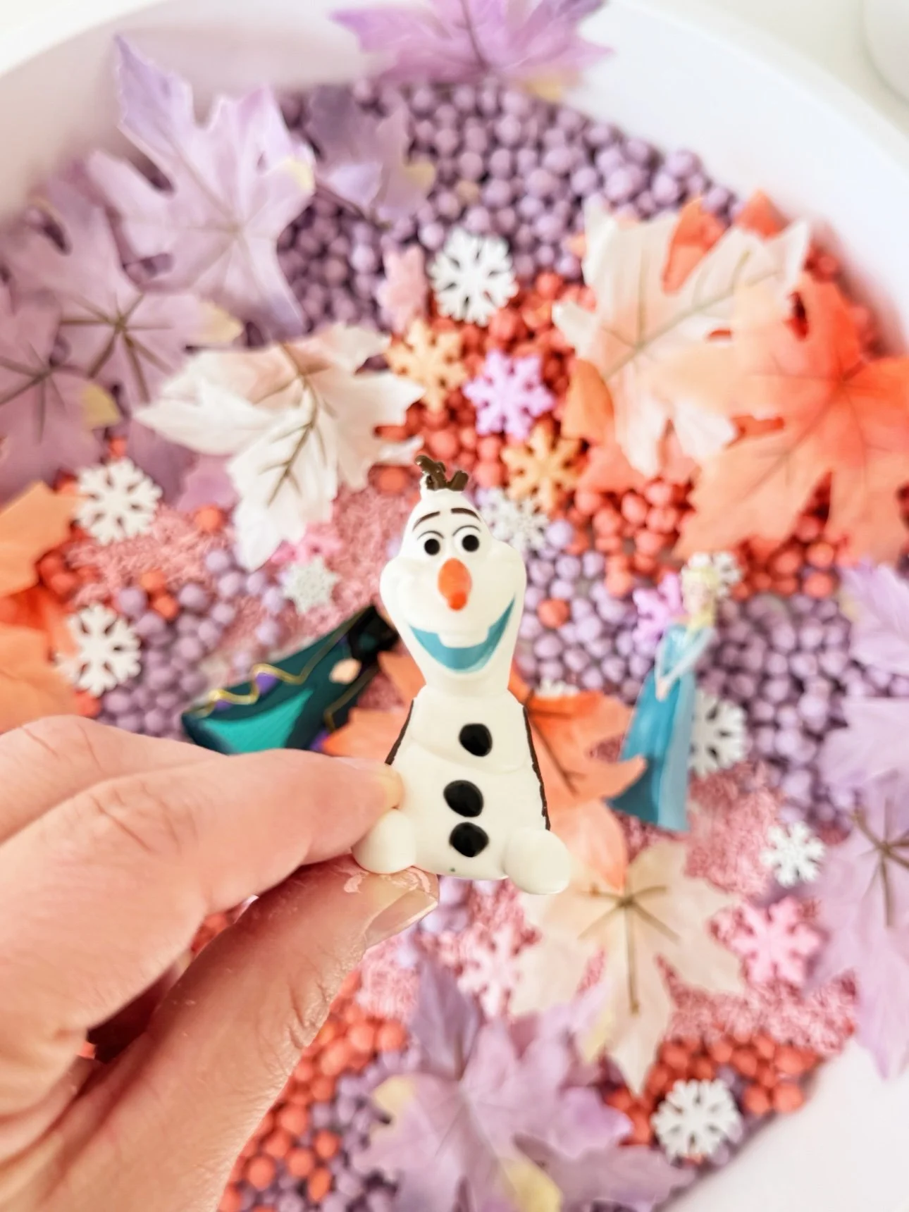 Olaf figurine held over the fall frozen sensory bin