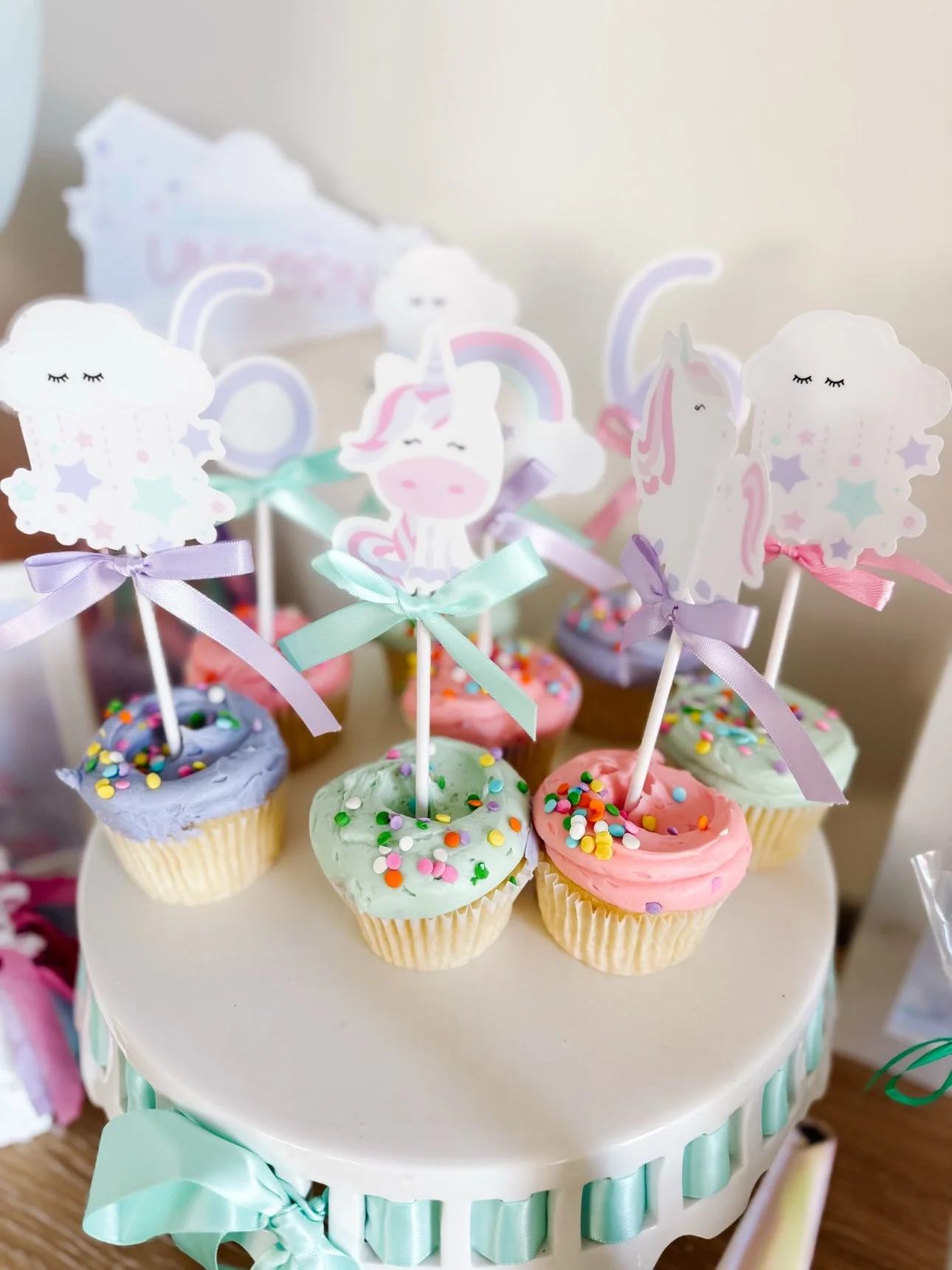 Frosted cupcakes with DIY unicorn toppers on a cake stand