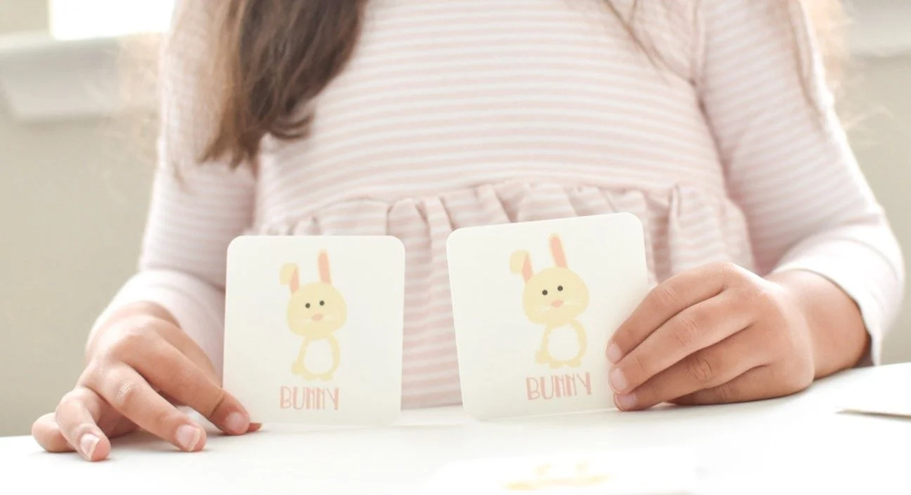Toddler holding matching memory game cards during a card hide-and-seek game