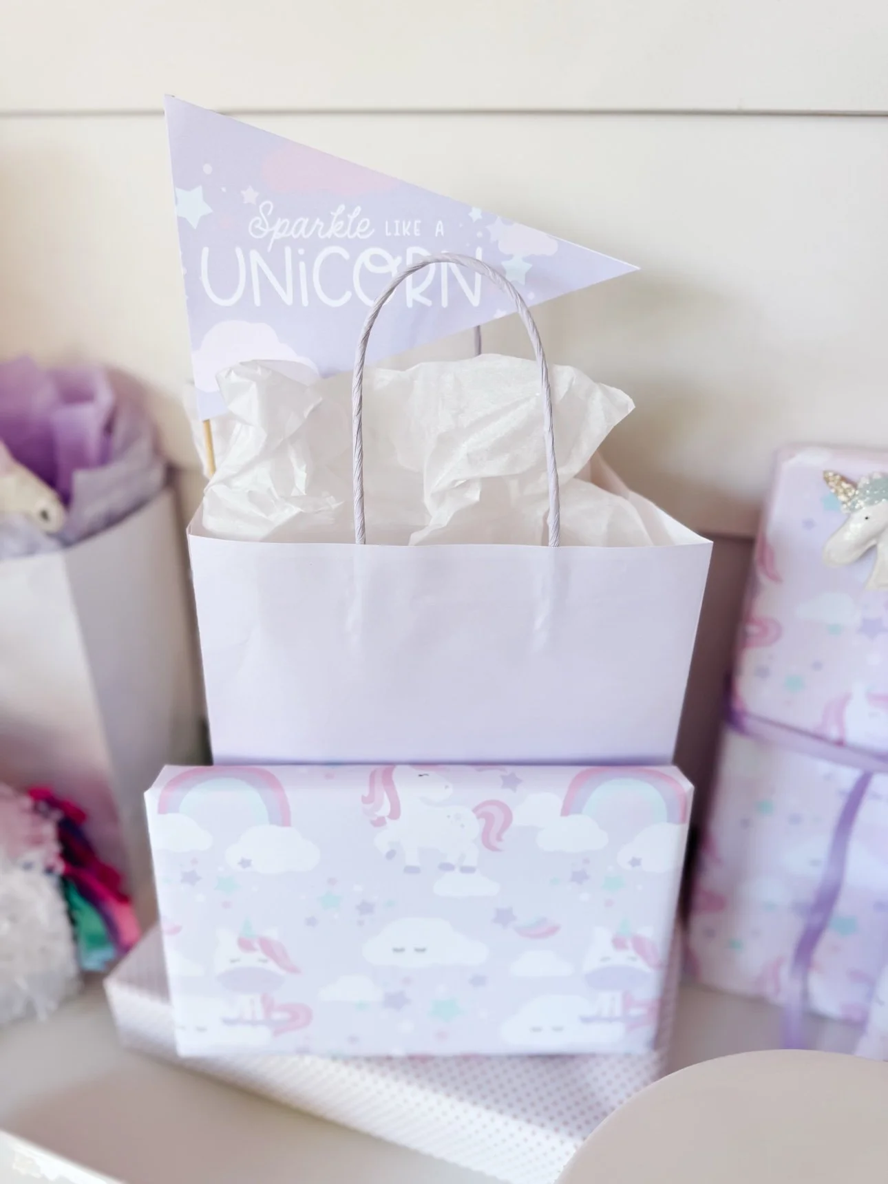 Unicorn pudding cups party sign with pastel napkins and plates