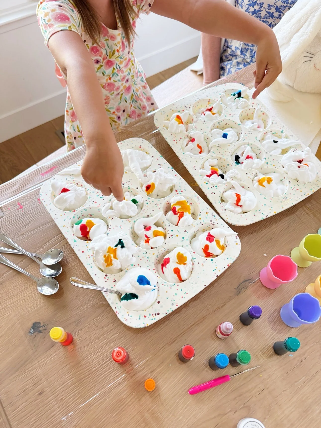 Adding drops of food coloring to shaving foam in a muffin tin