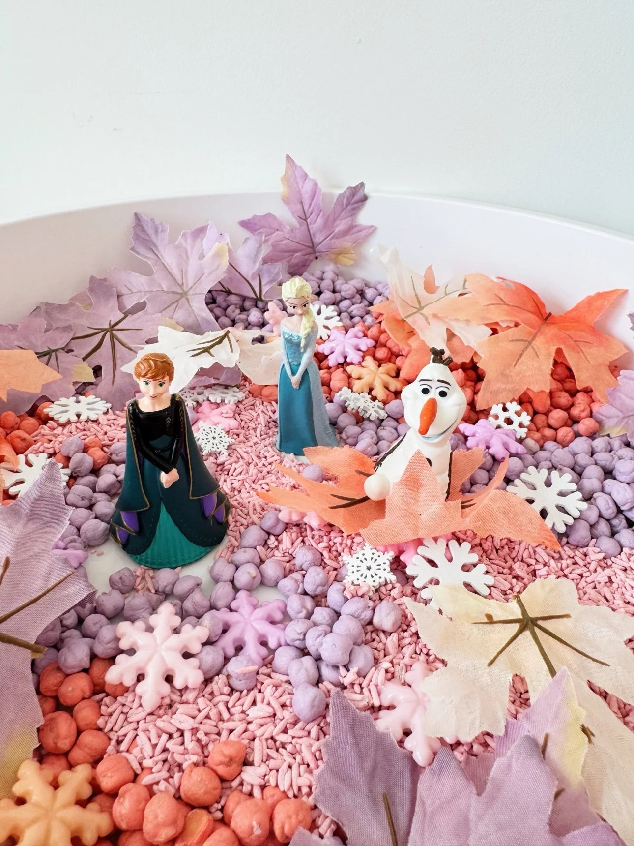 Anna, Elsa, and Olaf figurines standing in the fall frozen sensory bin
