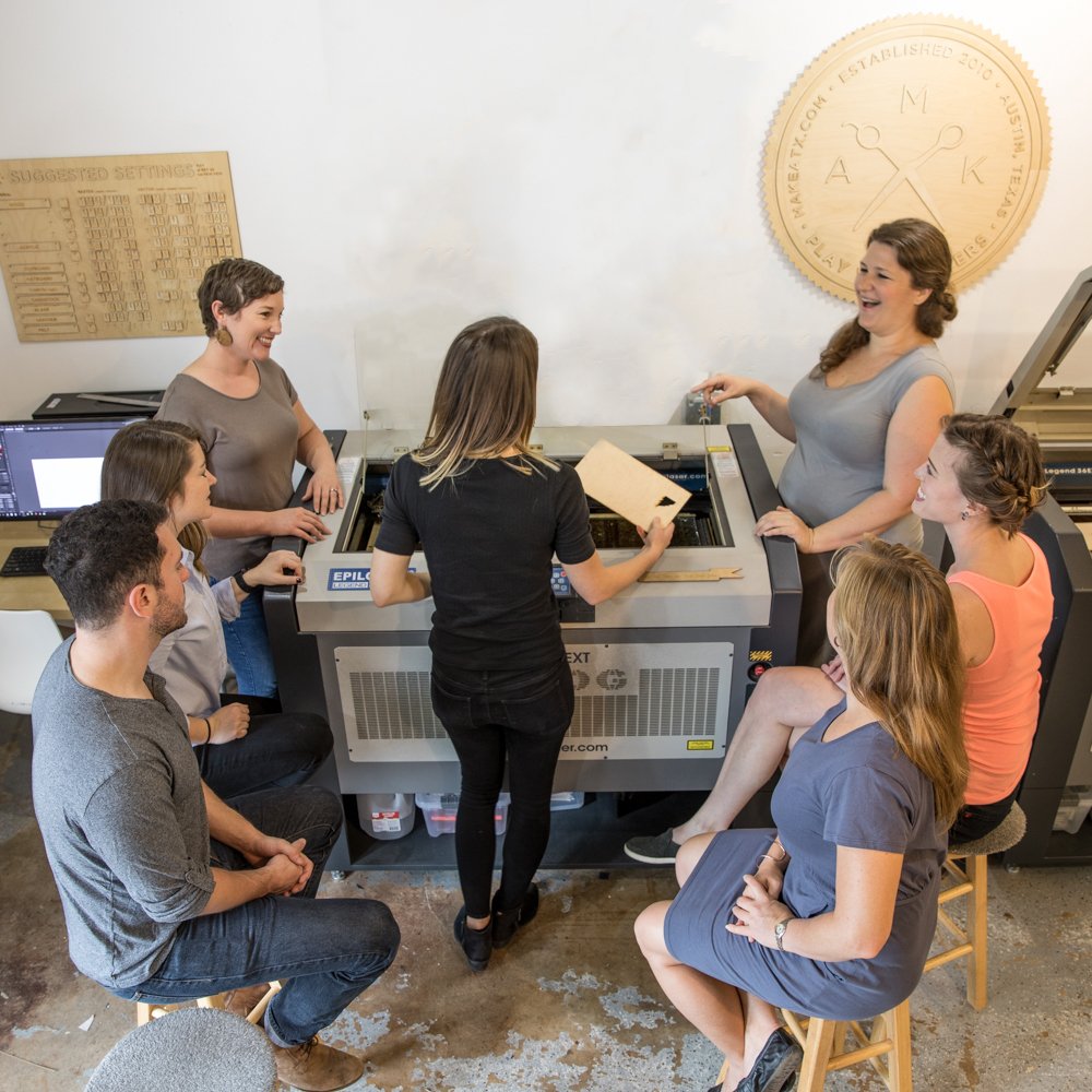 group of people gathered around a laser.