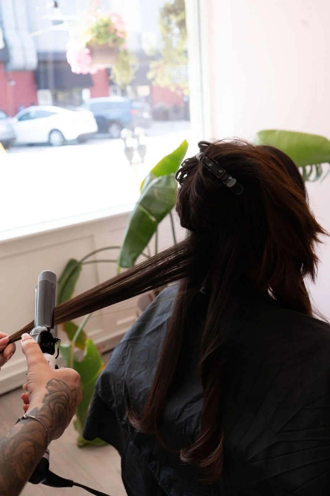 Stylist curling long hair extensions at Dollface in Oakville