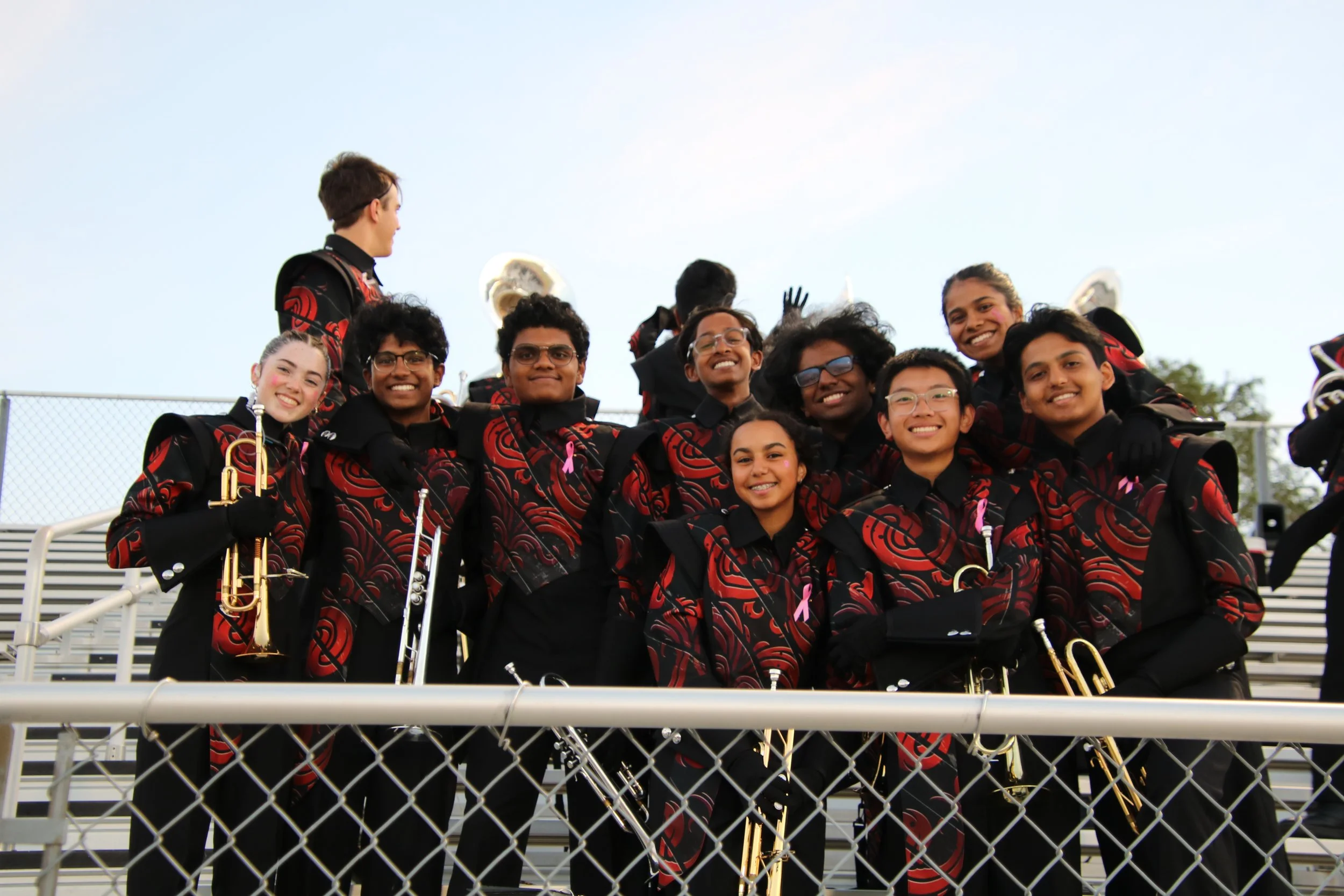 Liberty Redhawks brass players in uniform smiling together in the stands