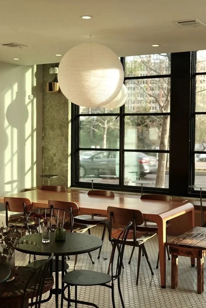 Sunlit tables, chairs and pendant lighting inside The Fifth Vessel