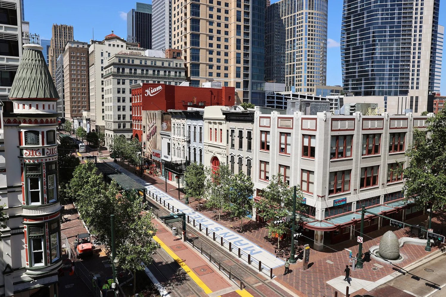 Historic storefronts, METRORail tracks and modern towers along Main Street in downtown Houston.