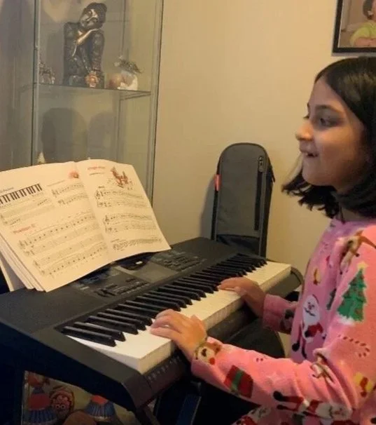 Young girl learning keyboard with online live music lessons