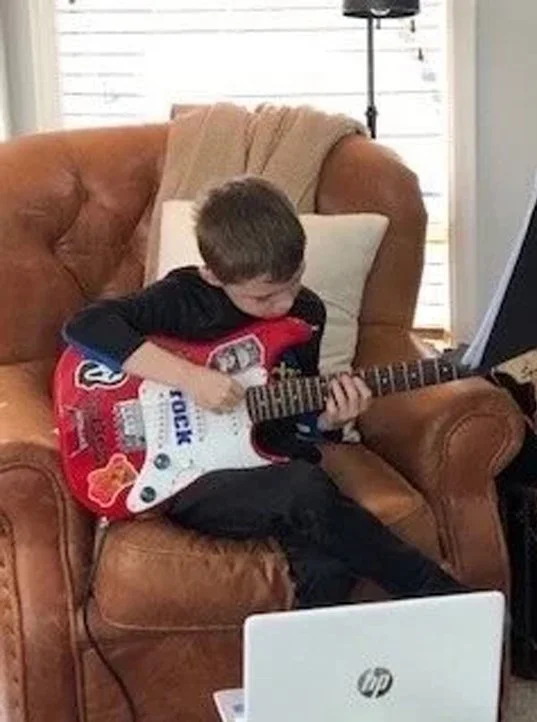 Young boy learning guitar lessons online