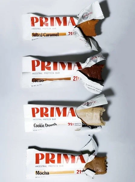 Four opened Prima bars in their current wrappers: Salted Caramel, Cacao, Cookie Dough and Mocha