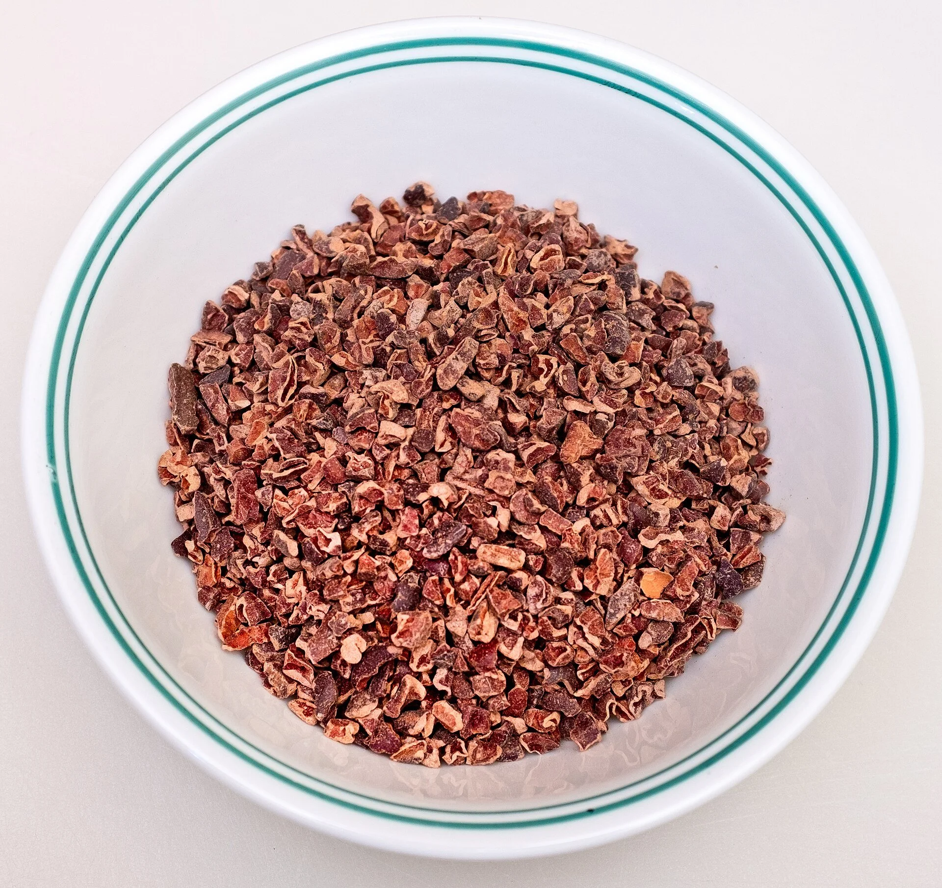 A white bowl of crushed cacao nibs