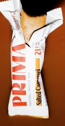 An opened Prima Salted Caramel bar in its current wrapper on an orange background