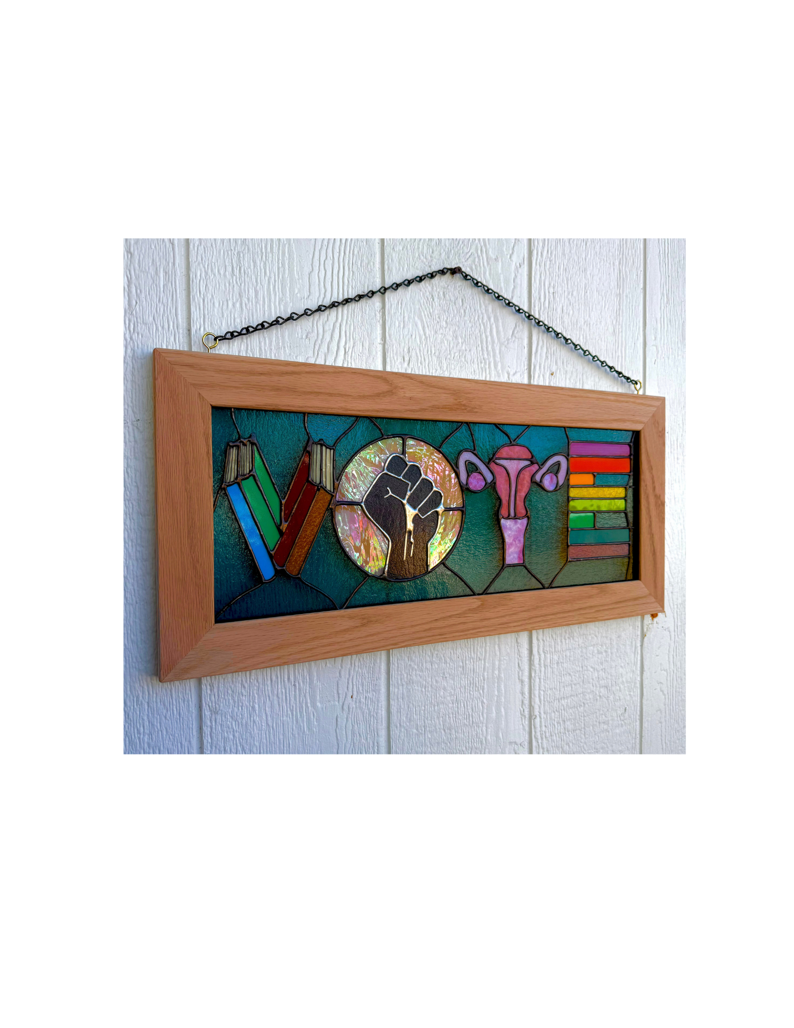 Raina’s finished VOTE stained glass panel with books, a raised fist, and a uterus