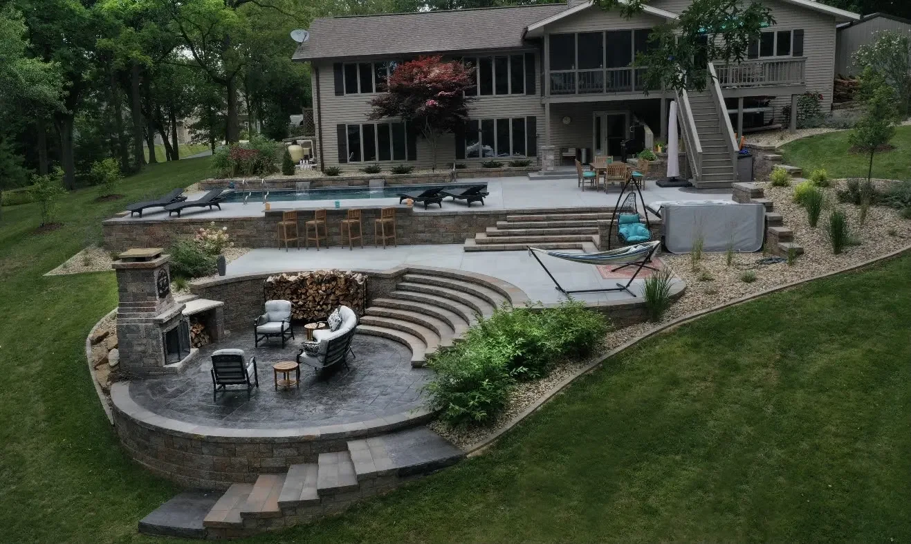 Tiered patio with curved retaining wall and stone steps at Danes Residence by Green View in Central Illinois
